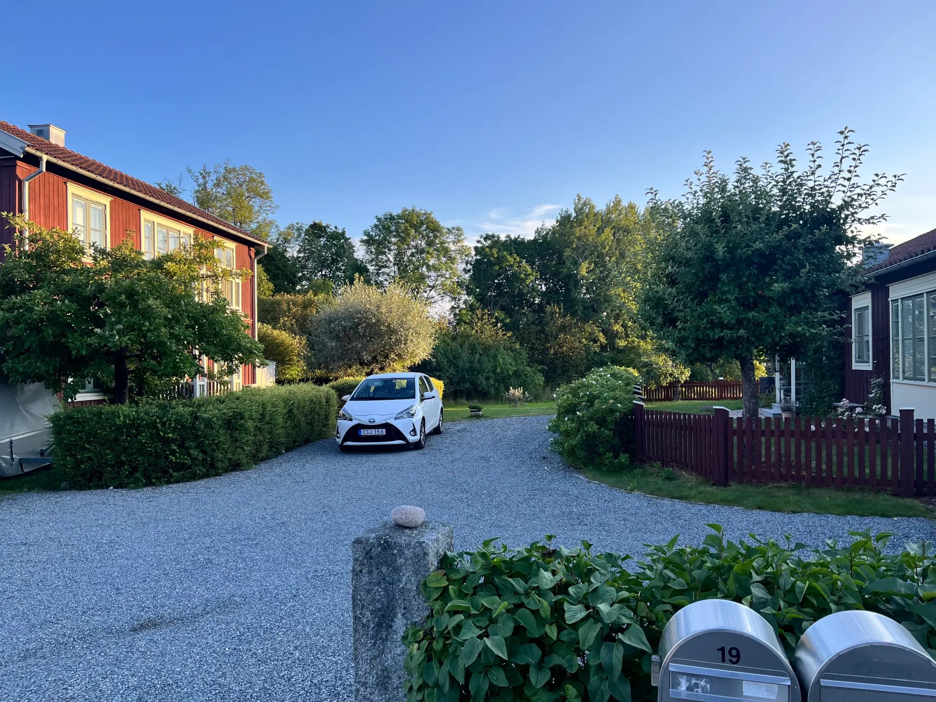 Grusuppfart mellan klippta häckar och röda hus på Pauli väg