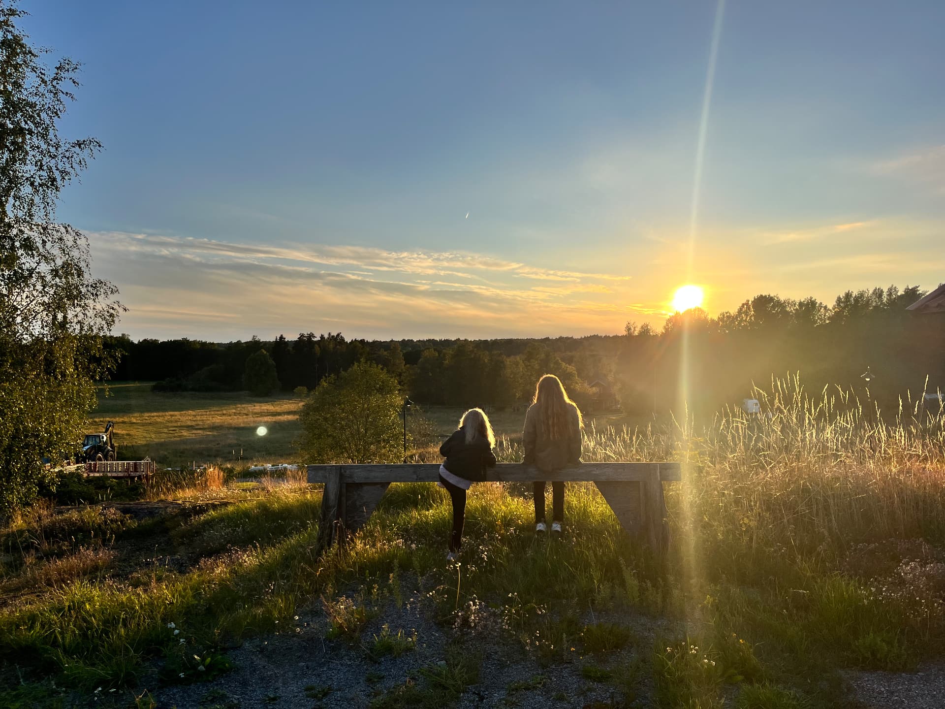 Två personer på en bänk med utsikt över fälten vid solnedgång